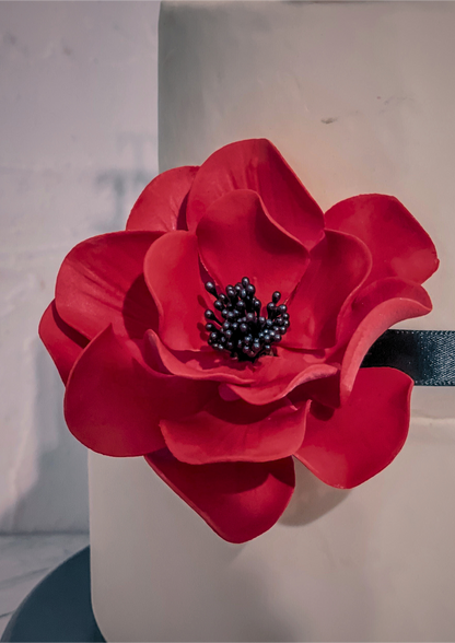 Red flower decoration on a cake with a gray background