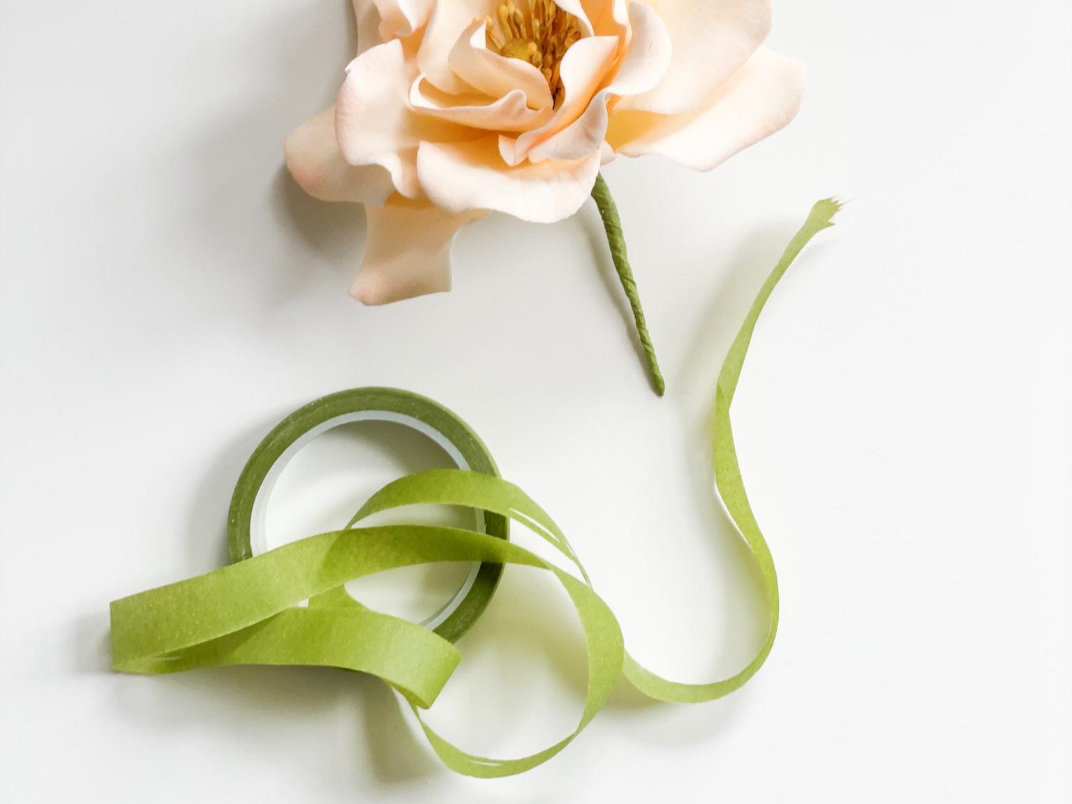 Light Green floral tape and peach-colored sugar flower on a white background